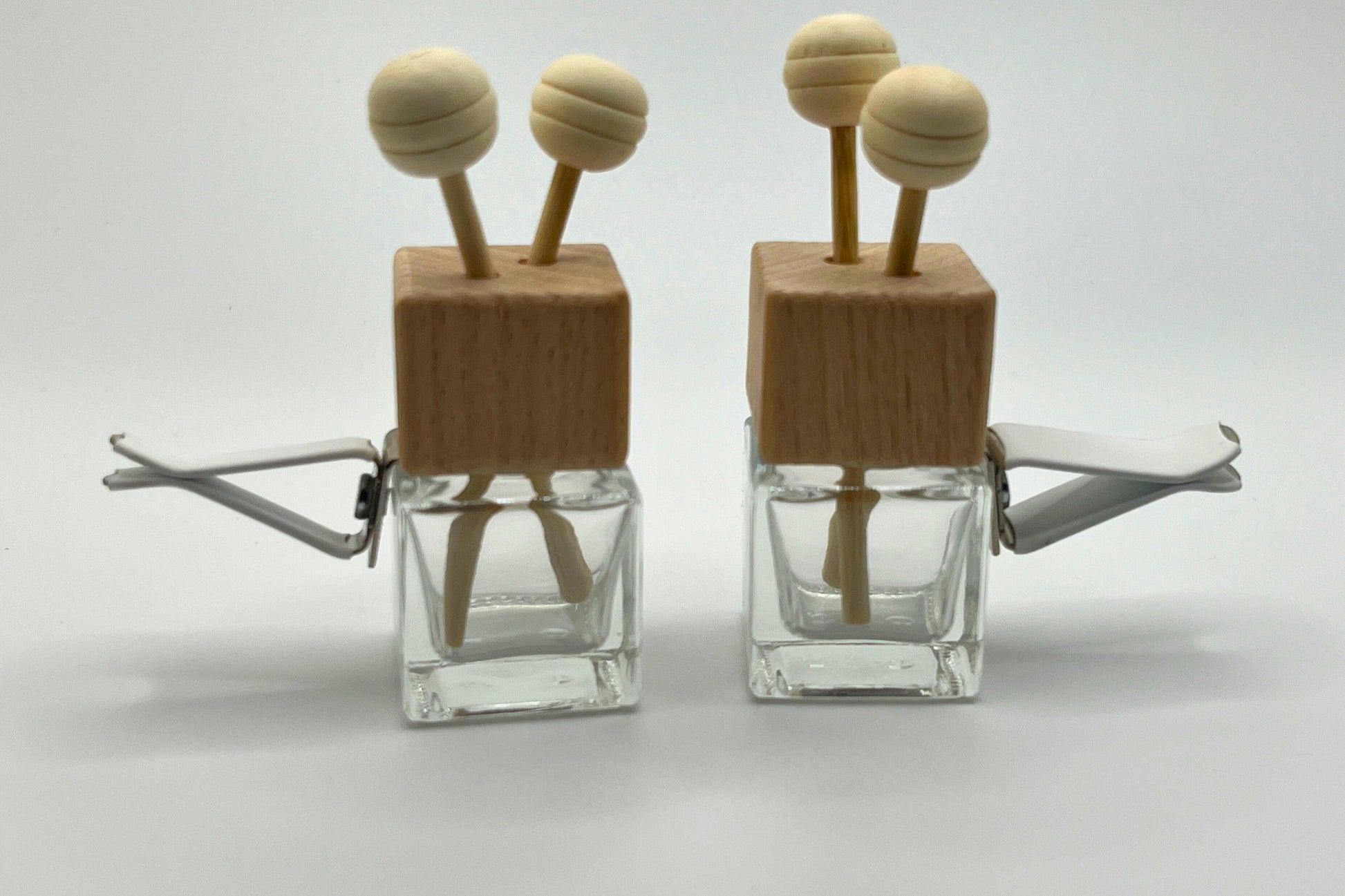 Customizable car vent diffuser with a natural wooden cap and sleek glass bottle. Handcrafted, offering long-lasting, personalized fragrances for cars, small spaces, or on-the-go aromatherapy. Elevate your drive with a touch of elegance and freshness.
