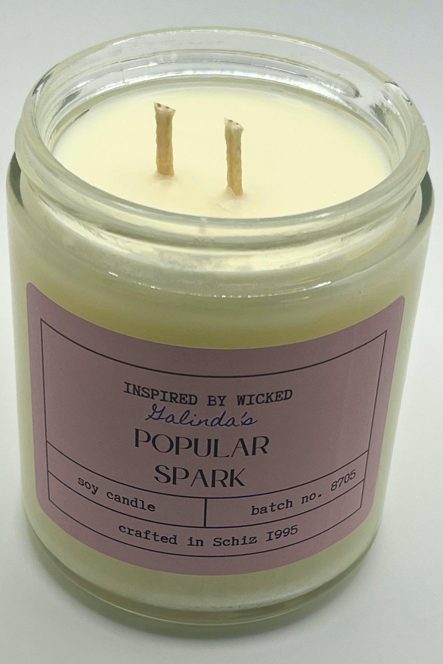 Handcrafted soy candle inspired by Wicked's Galinda, featuring a Popular Spark pink label. Infused with enchanting fragrances, it adds a touch of magic and whimsy to your space. Perfect for unique gifting or personal enjoyment.