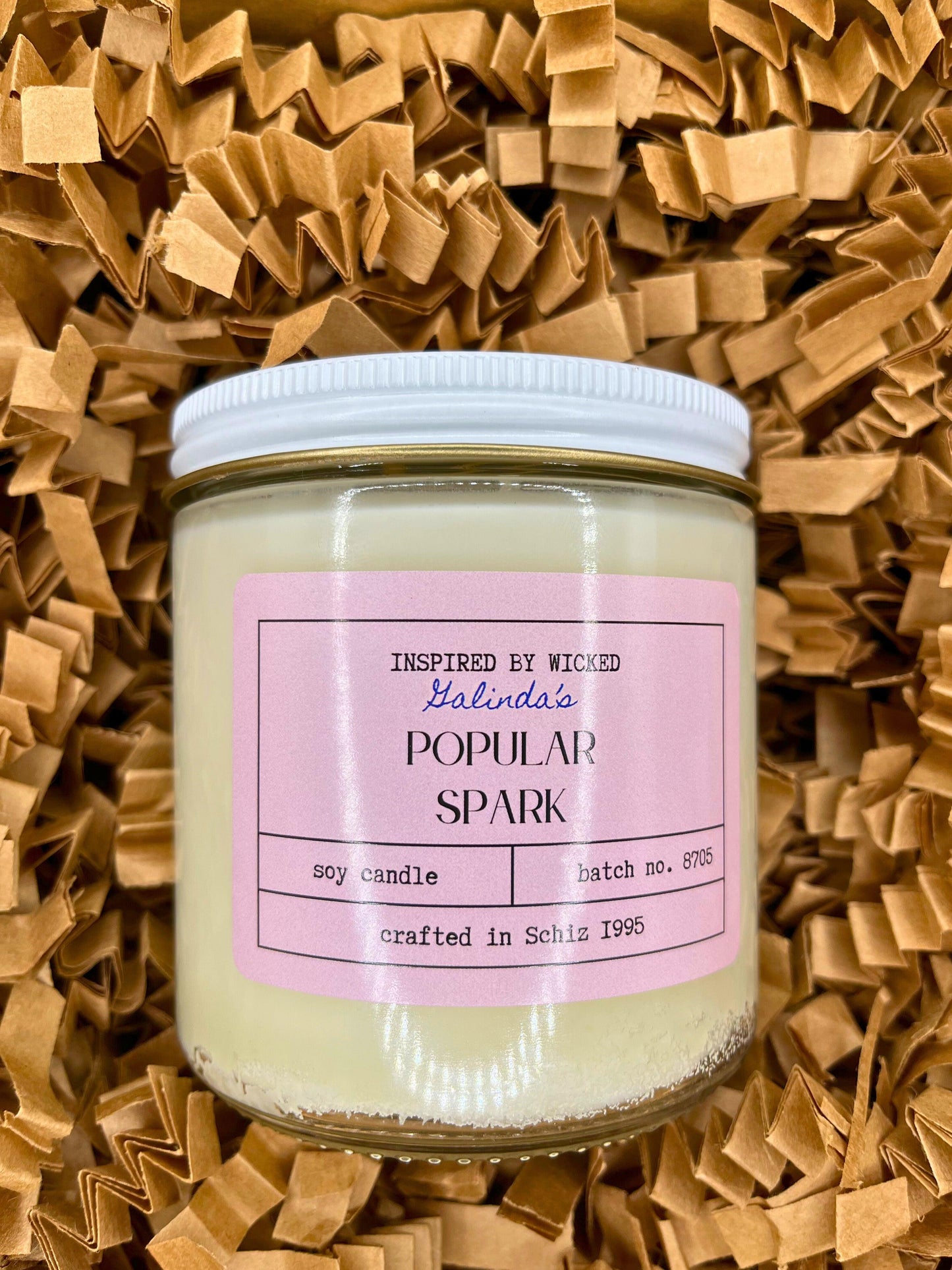 Handcrafted soy candle inspired by Wicked's Galinda, featuring a Popular Spark pink label. Infused with enchanting fragrances, it adds a touch of magic and whimsy to your space. Perfect for unique gifting or personal enjoyment.